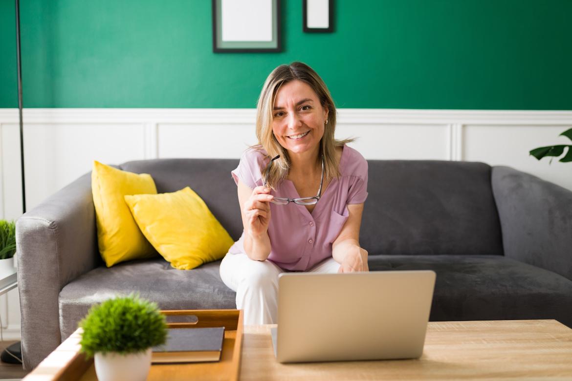 Frau Sofa mit Laptop auf Tisch lächelt in Kamera