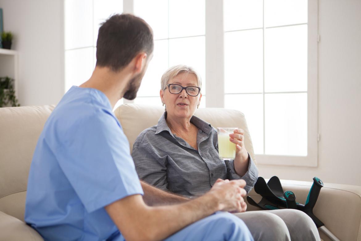 Arzt spricht mit Seniorin auf Sofa