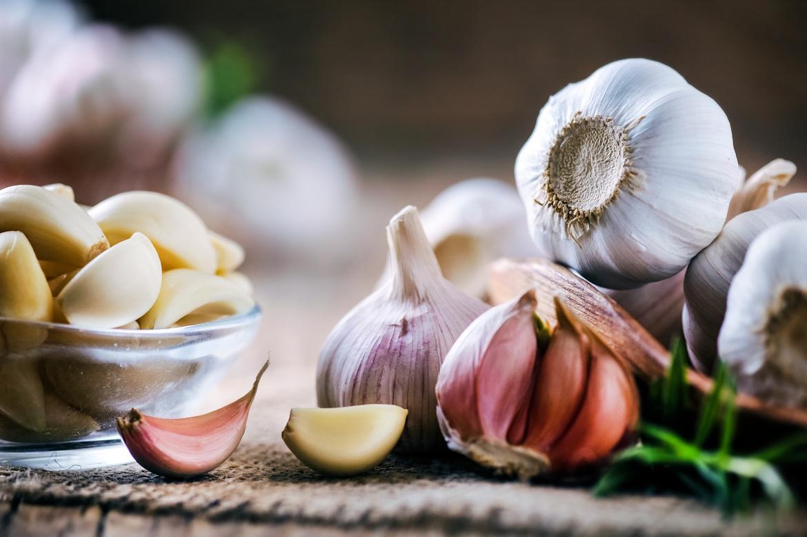 Knoblauchzehen und -knollen auf einem rustikalen Tisch