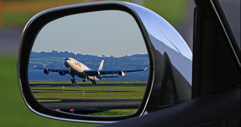 Flugzeug spiegelt sich im Rückspiegel eines Autos
