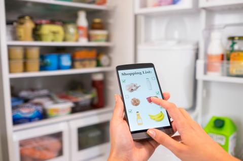 Digitale Einkaufsliste erstellen vor geöffnetem Kühlschrank