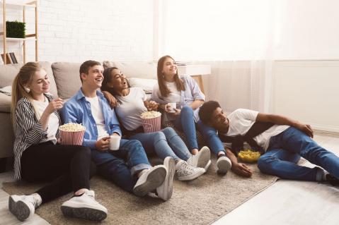 Junge Leute mit Popcorn sitzen auf dem Fußboden - Rundfunkbeitrag