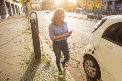 Frau mit Elektroauto an Ladesäule