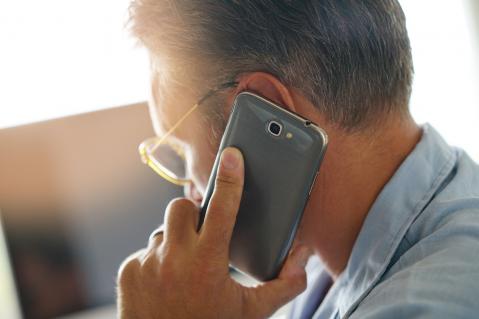 Schmuckbild: Mann mit Smartphone am Ohr, von schräg hinten zu sehen.