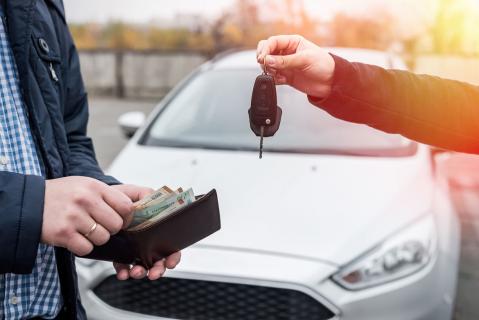 Mann mit offenem Portemonnaie, zweiter Mann mit Autoschlüssel vor Auto zu Artikel: Gebrauchtwagenverkauf online: Preiseinschätzung nicht bindend