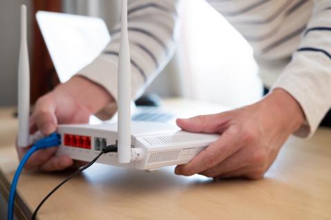 Mensch steckt Kabel in Glasfasermodem