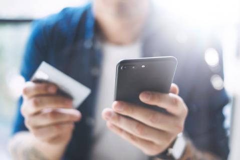 Mann mit Smartphone und Kreditkarte in der Hand zu Artikel: In-App-Käufe - 5 Dinge, die Sie wissen sollten