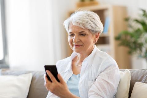 Ältere Dame mit Smartphone auf Sofa zu Artikel: Prepaid-Vertrag - Karte von Wenignutzern nach Inaktivität gesperrt