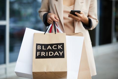 Frau mit Einkaufstüten. Auf einer steht Black Friday