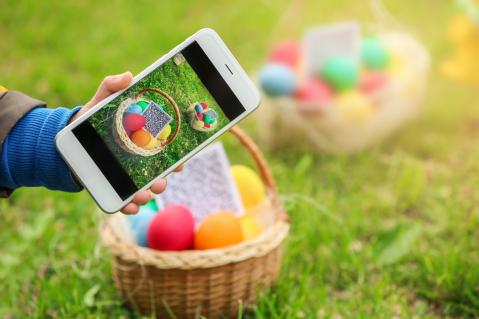 Korb mit Eiern und QRCode auf Rasen, im Vordergrund Smartphone mit Foto davon zu Artikel: Smartphone Rallye zu Ostern