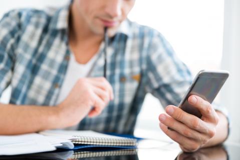 Mann mit Smartphone und Block zum Rechnen