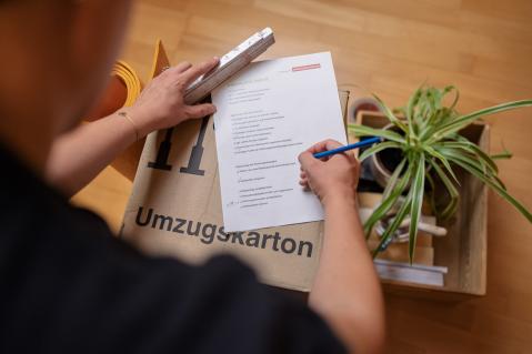 Umzugskarton mit Checkliste, Person im Hintergrund