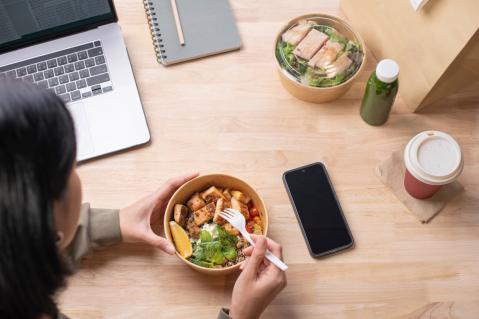 Frau im Büro isst gesundes Mittagessen 