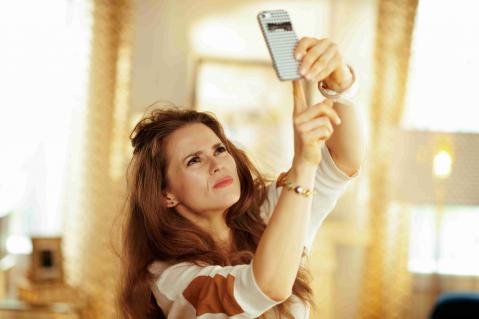 Frau hebt Handy in die Höhe in ihrere Wohnung für besseren Empfang