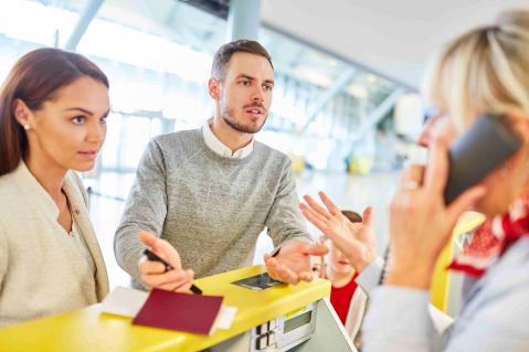 Familie diskutiert am Airline Schalter Flughafen mit Servicepersonal