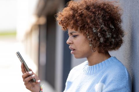 Mädchen schaut verstört auf ihr Telefon