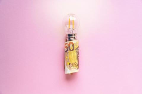 Glühbirne in 50 Euro Schein gewickelt auf rosa Hintergrund