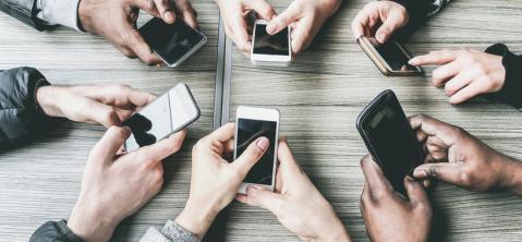 Viele Hände im Kreis mit Smartphones