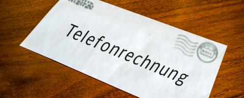 Telefonrechnung liegt auf Holztisch